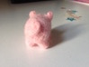 The rear of a needle-felted pink pig with a curly tail.